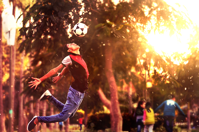  a kid hitting a black and white soccer ball with thier head