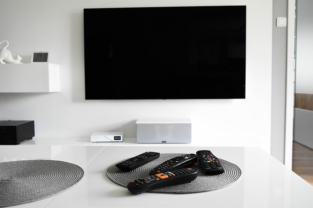 white room witha large flatscreen TV and a coffee table with TV remotes on it