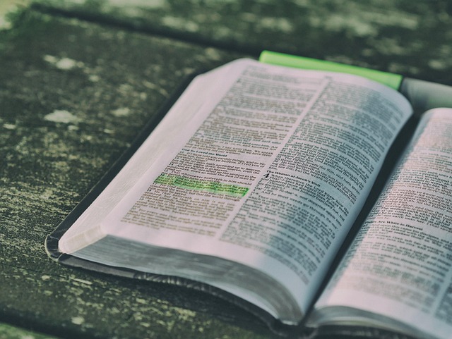 a picture of an open bible with green hightlighter sitting on a wood surface