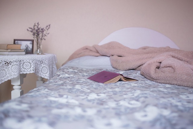 bed with book on it and nightstand on the side with lavender on the nightstand