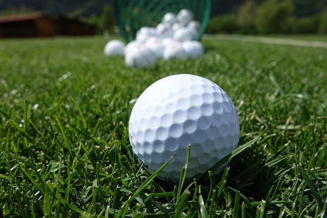 A golf ball on turf grass with a pile of more golf balls behind it.