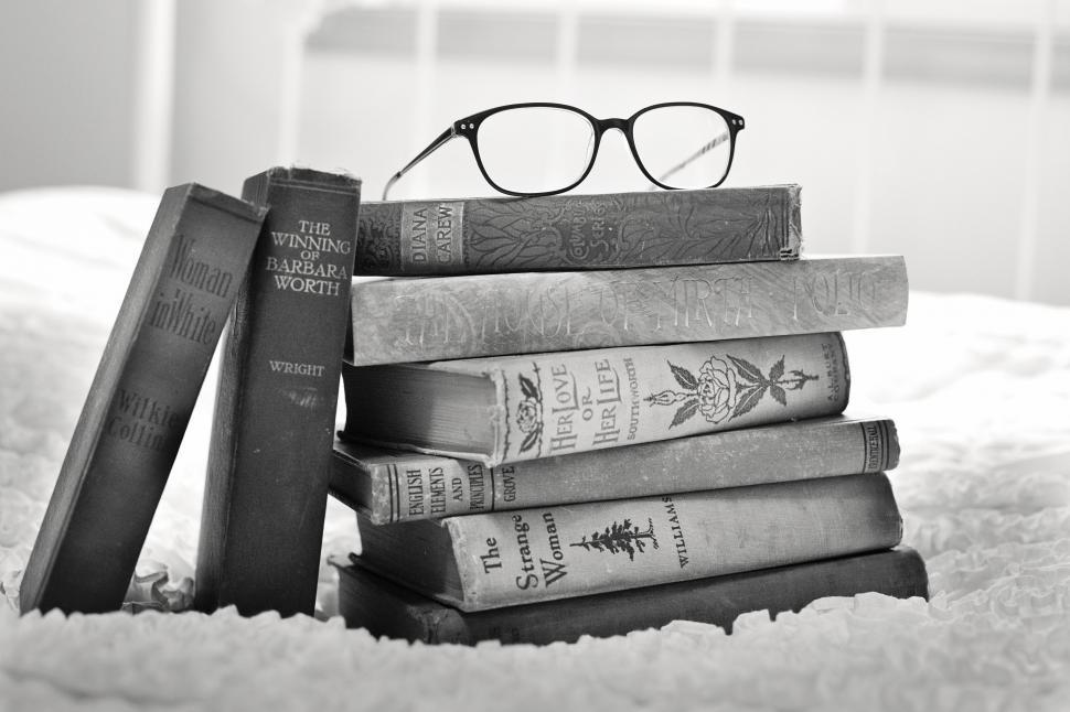 Stack of books with pair of glasses on top.