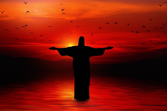 Christ statue in water with a sunset