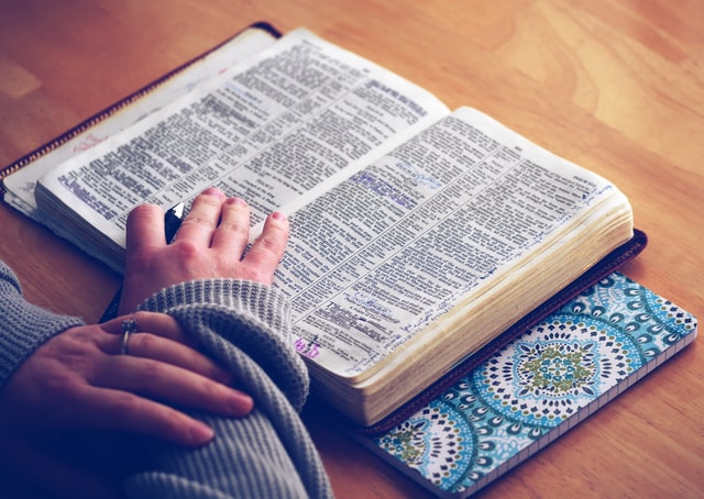 person reading bible with blue notebook