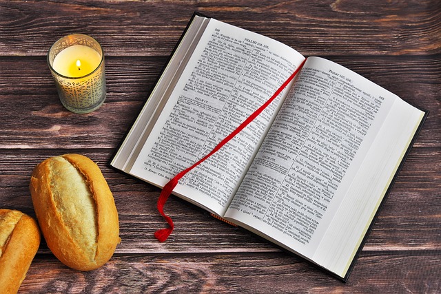 A picture of a bible with two pieces of bread along with a candle next to the bible