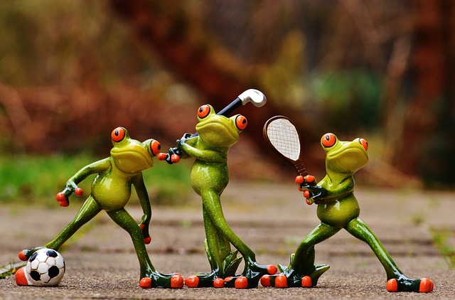 3 frogs holding a tenis raket, a golf club, and kicking a soccer ball