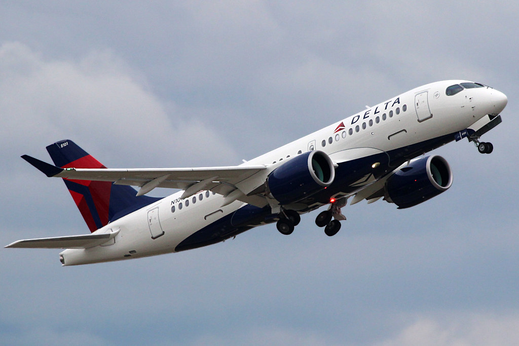 Delta A220-100 departing out of an airport retracting its landing gears