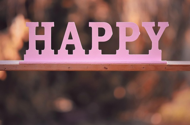 A pink wooden sign that says happy on it. 