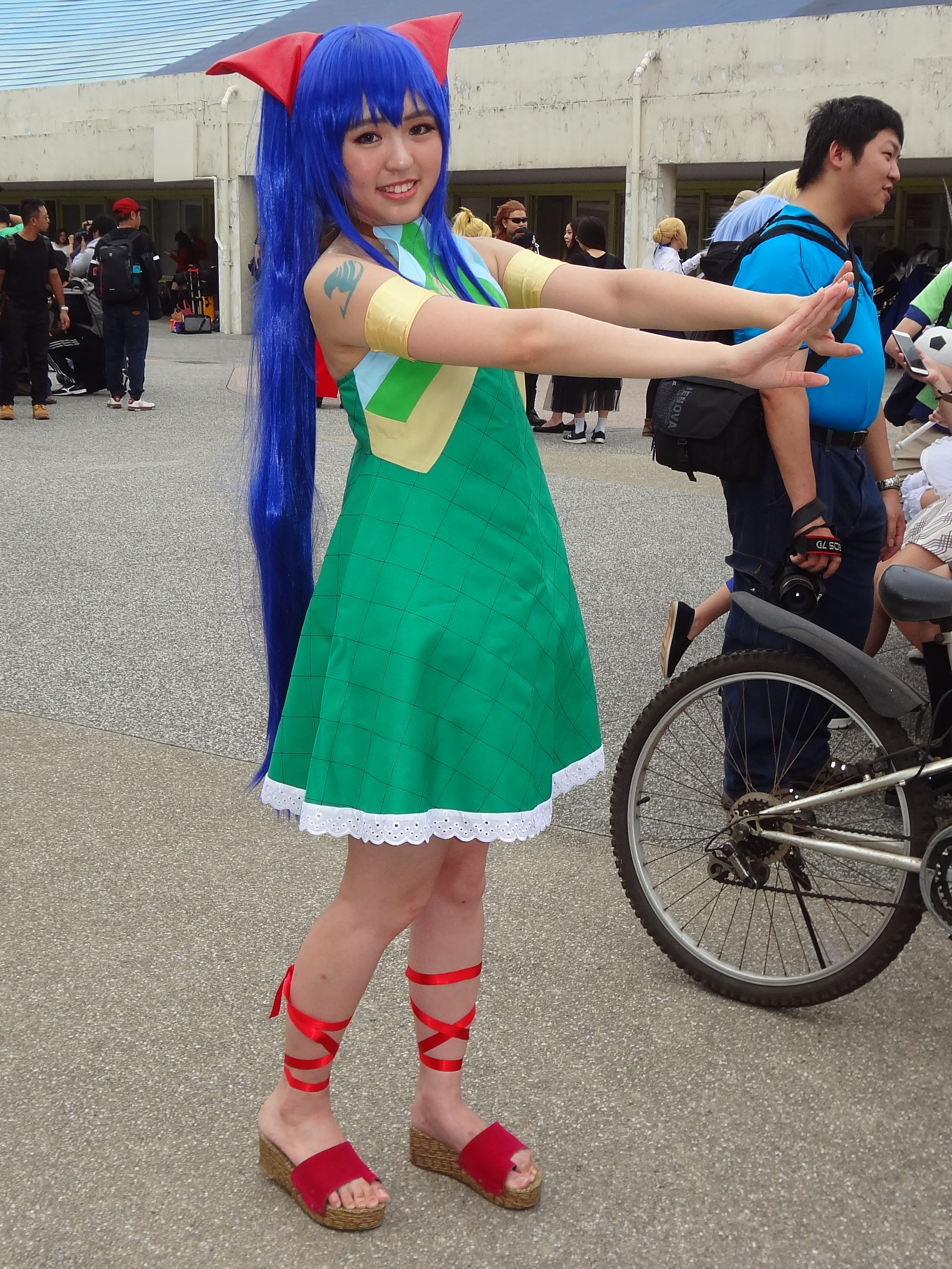 a girl in a green, yellow and blue dress and yellow arm band with blue hair and red accsesories and red shoes