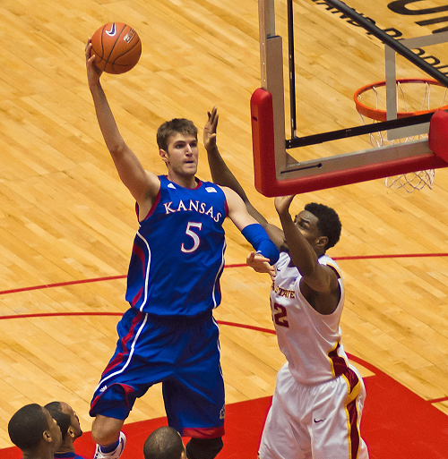 Picture of a basketball player throwing the ball into the hoop while performing a hooking motion. 