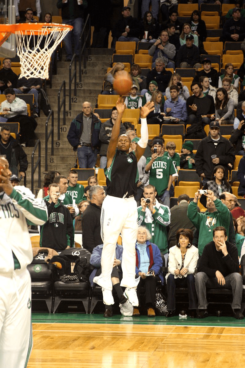 Picture of a player jumping in the air while throwing the basketball.