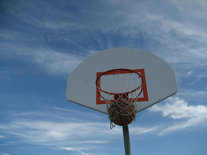Image of a basketball going through a net on a basketball hoop. 