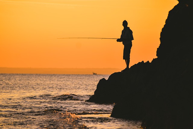 Man fishing on a rock by the ocean