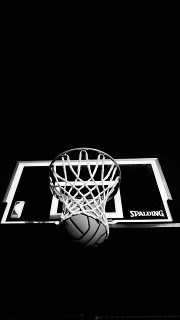 black and white picture of basketball going through hoop